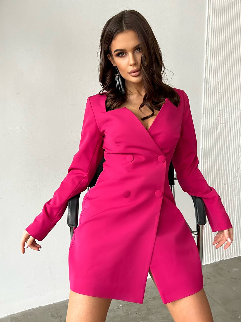 Woman wearing a bright pink dress with long sleeves against a white background