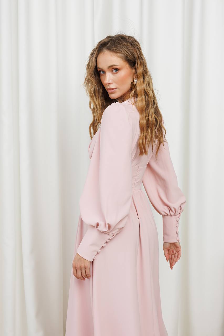 Woman wearing a pink dress against a white curtain background