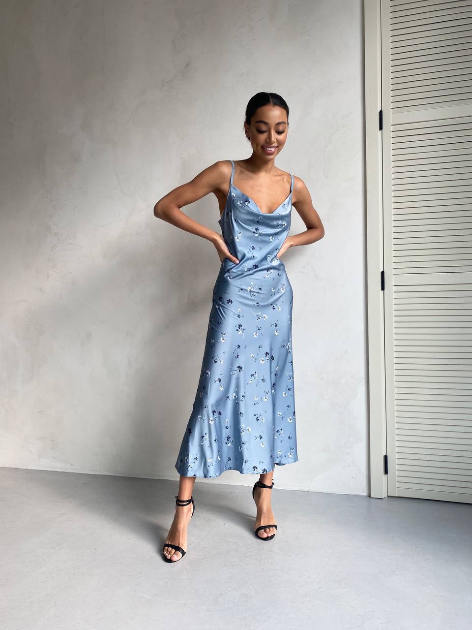 Woman wearing a light blue dress with a subtle pattern against a neutral background