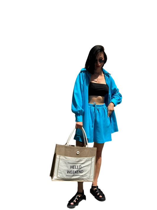 Woman in blue outfit holding a 'Hello Weekend' bag on a white background
