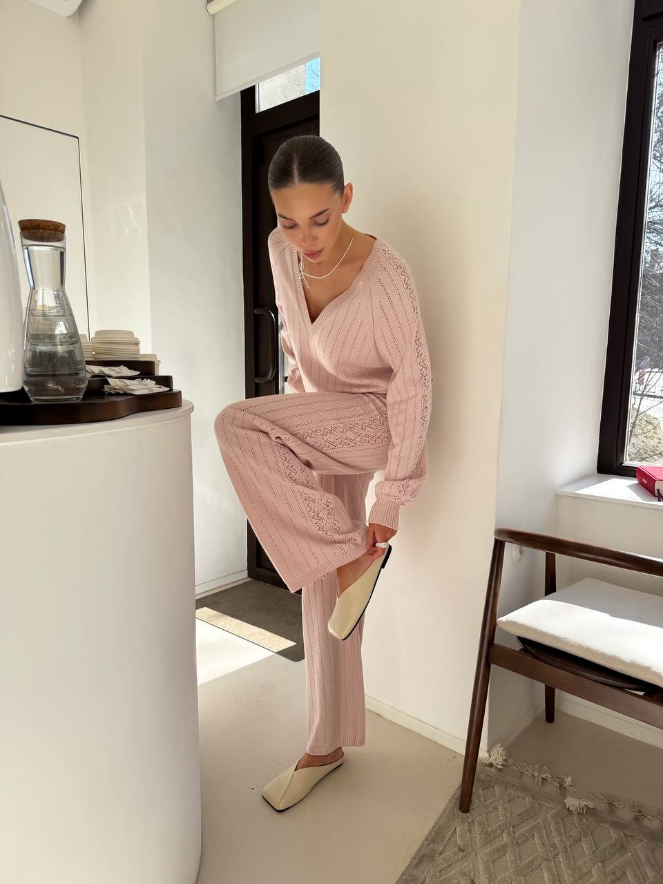 Woman in a pink outfit standing in a modern interior setting