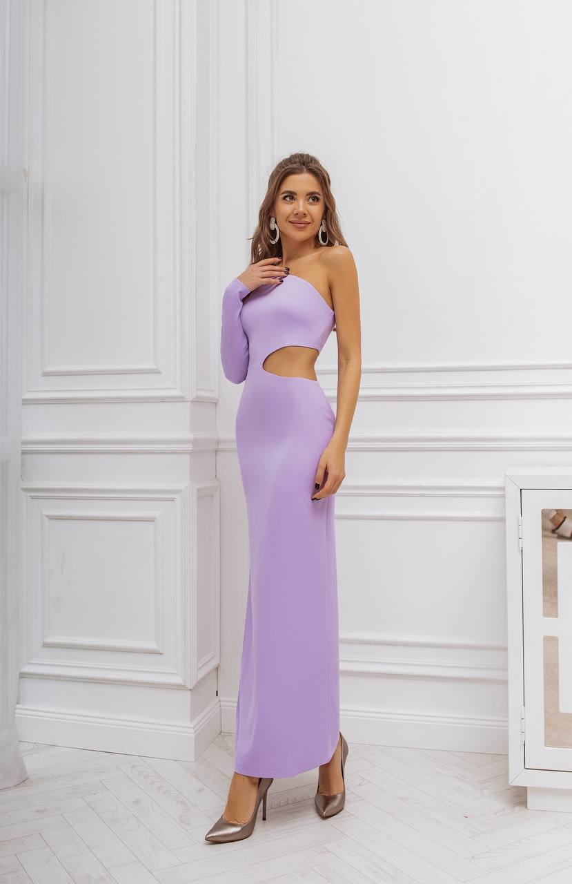 Woman wearing a long, light purple one-shoulder dress against a white wall.