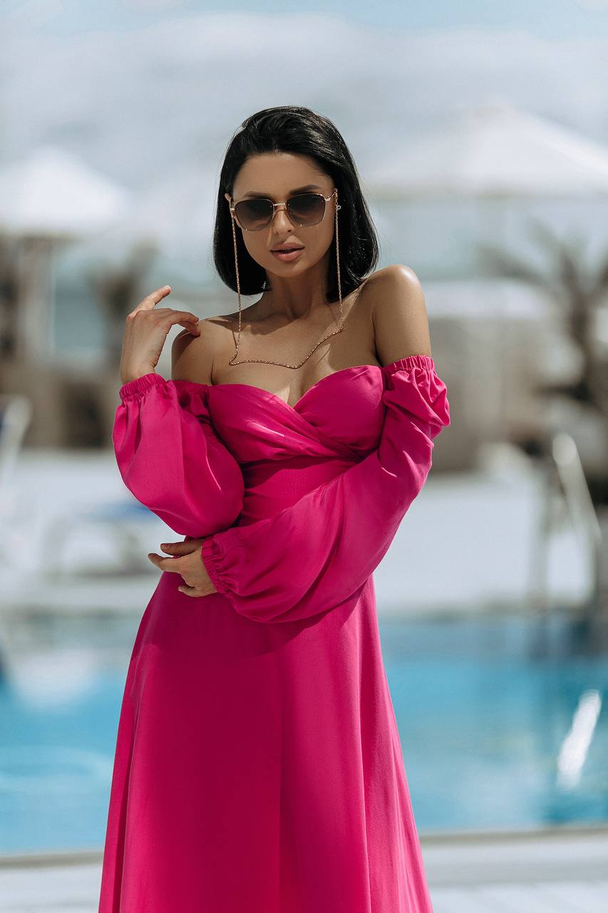 Woman in a pink dress standing by a pool with blurred background