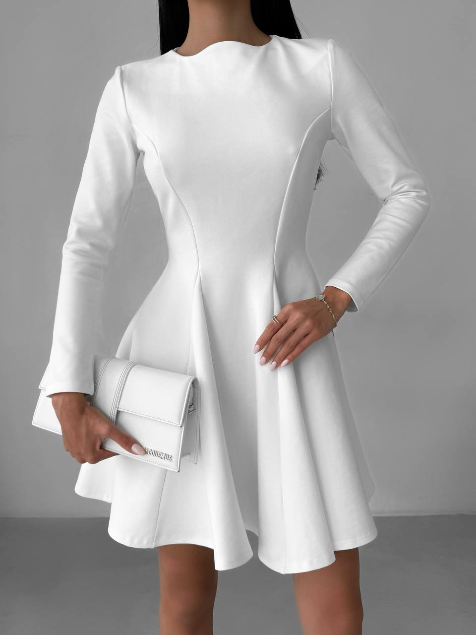 White dress with long sleeves worn by a person against a gray background