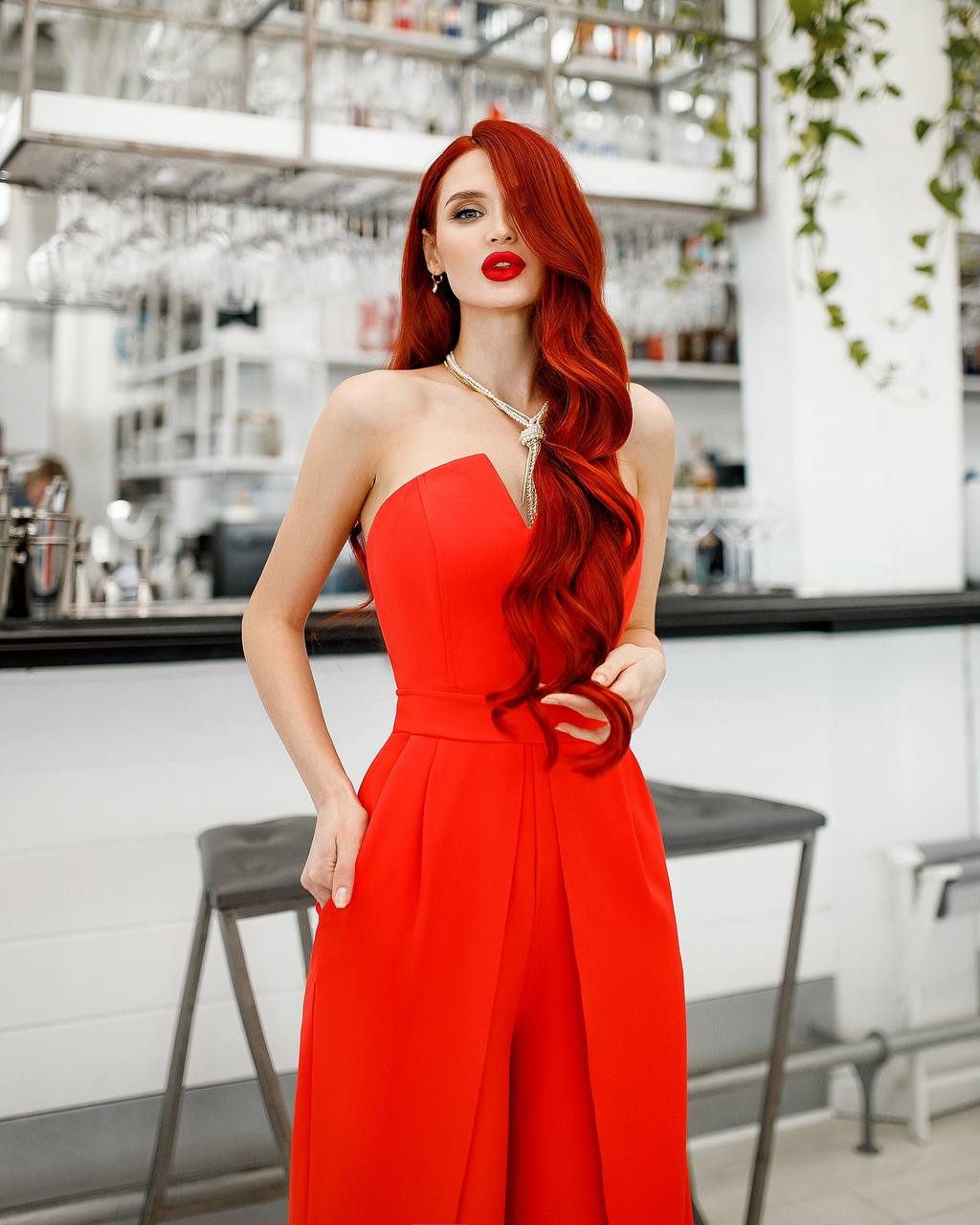 Woman in a red jumpsuit with long red hair in a kitchen setting