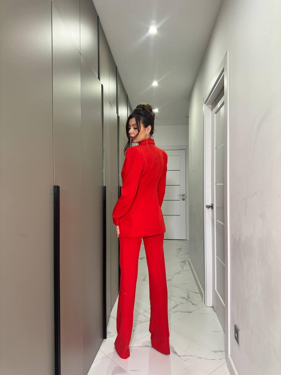 Person wearing a red outfit standing in a hallway.