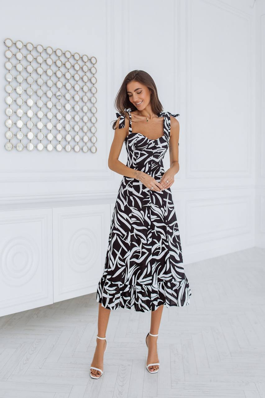 Woman wearing a black and white patterned dress in a minimalistic room.