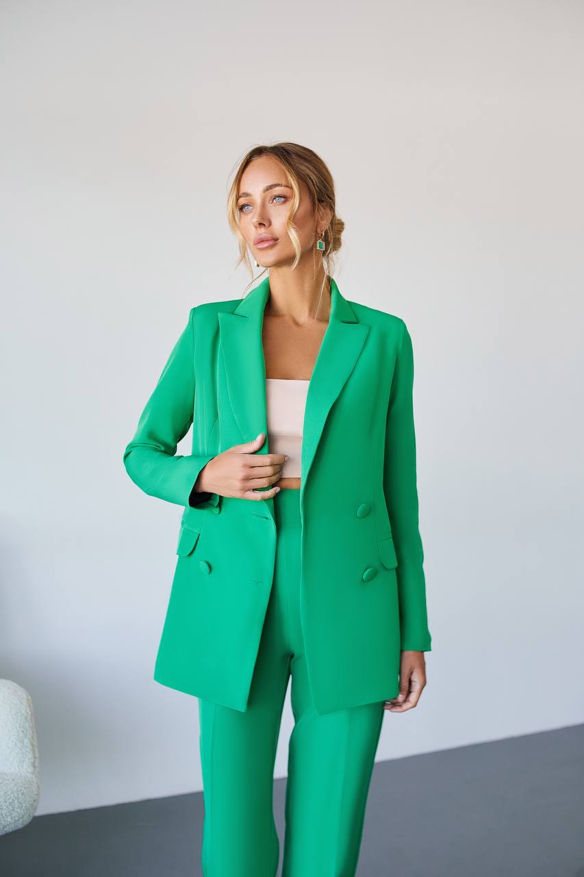 Woman wearing a green suit against a plain background