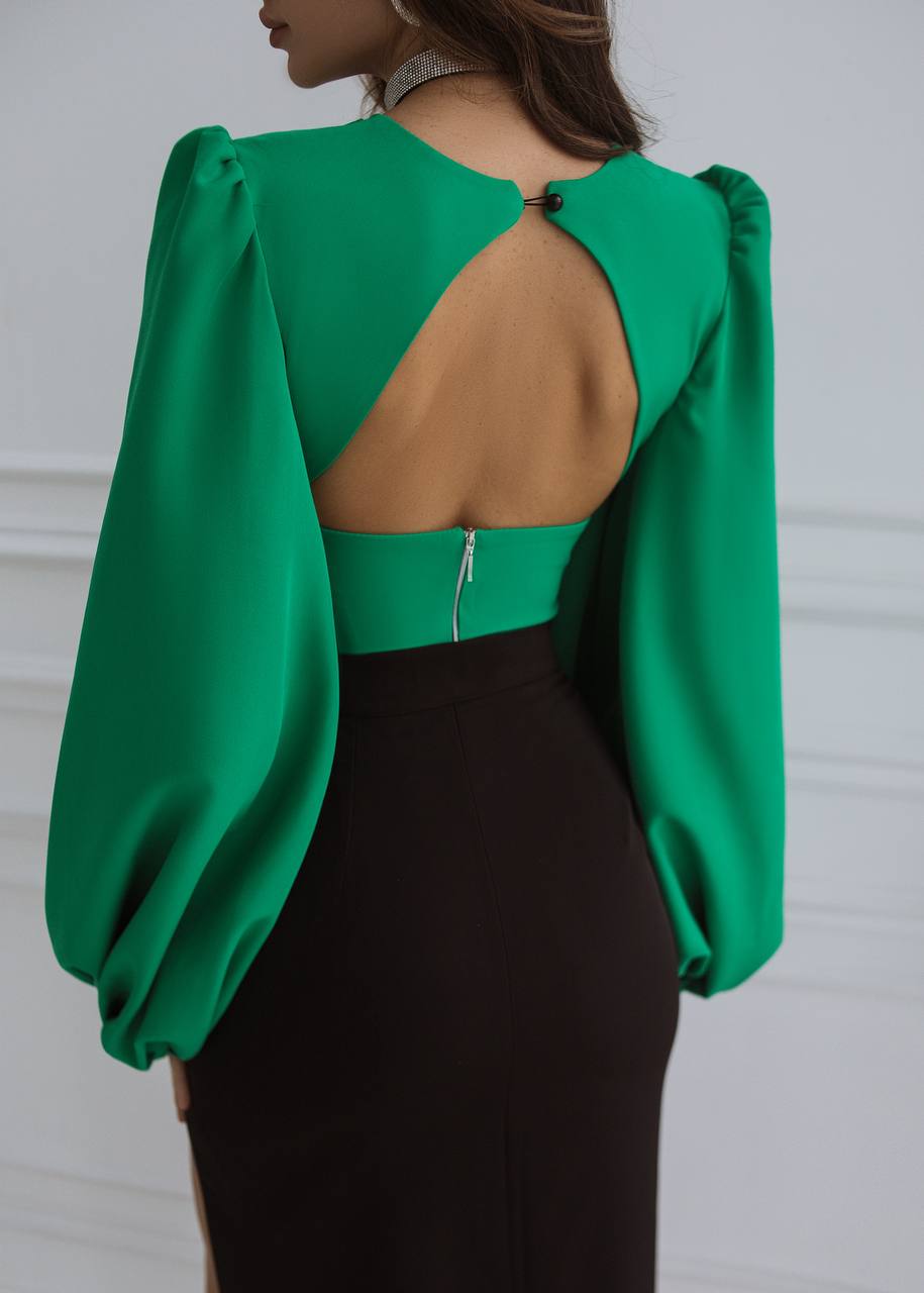 Green blouse with open back and puffed sleeves worn by a person on a white background