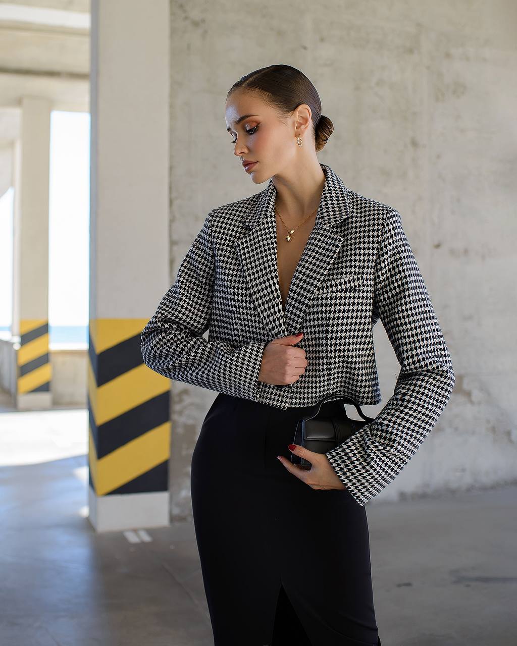 Woman wearing a houndstooth patterned jacket in an industrial setting