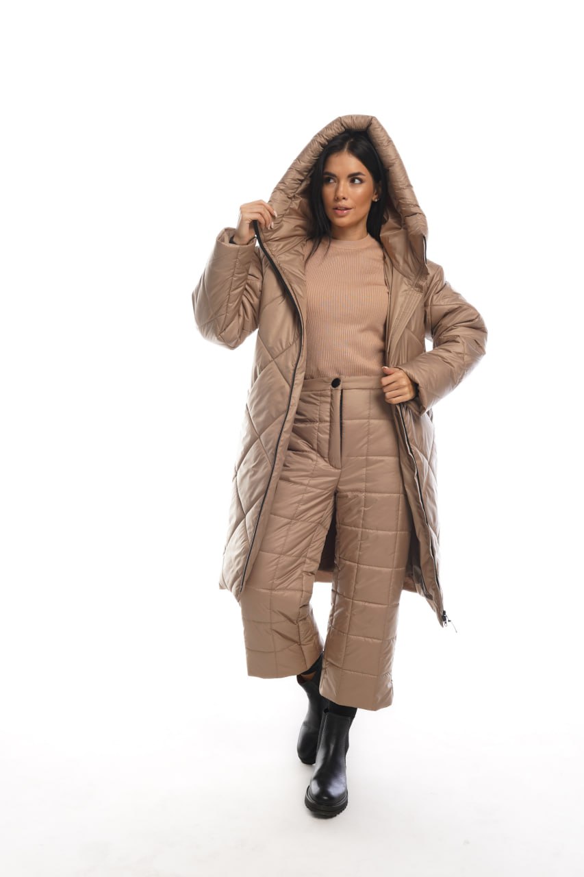 Woman wearing a beige quilted coat and pants on a white background