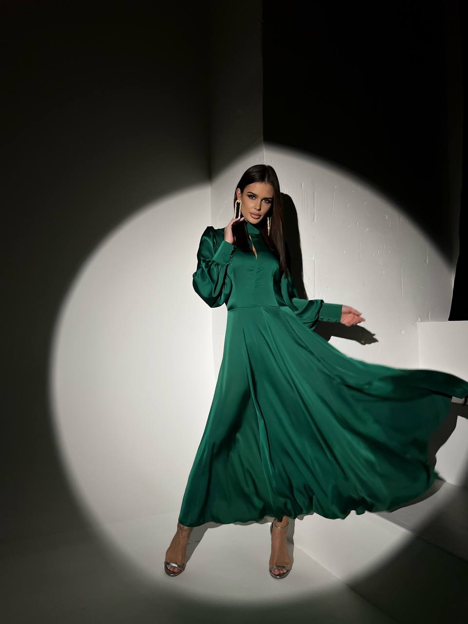 Woman wearing a green dress standing in a spotlight against a dark background