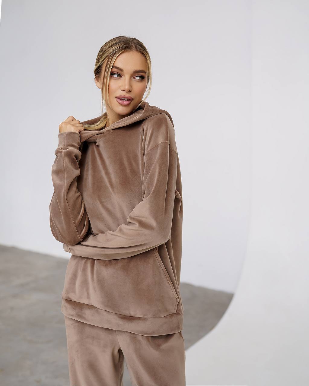 Woman wearing a brown velour tracksuit against a plain background