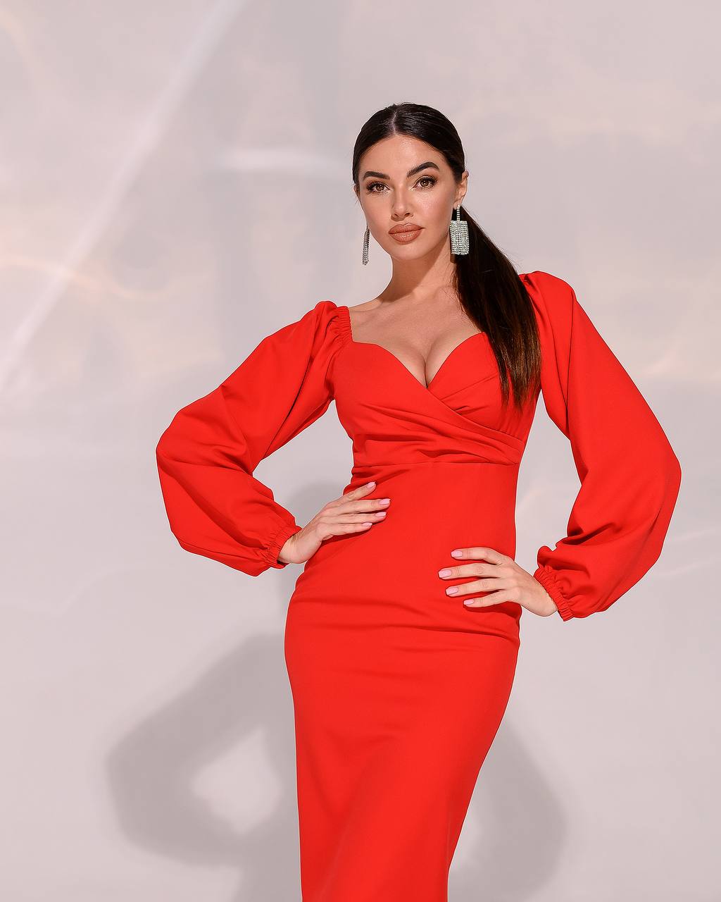 Woman wearing a red dress with long sleeves on a light gray background