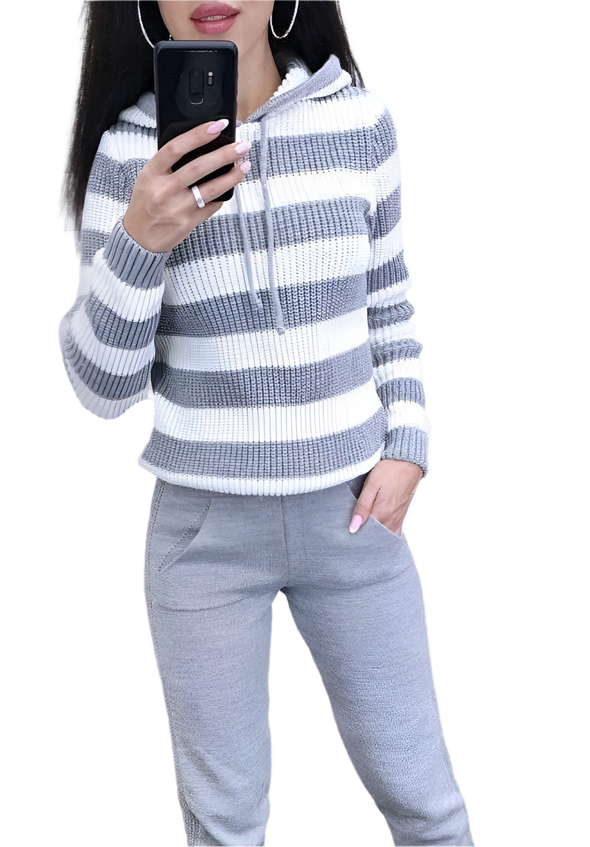 Person wearing a gray and white striped sweater and gray pants, holding a phone.
