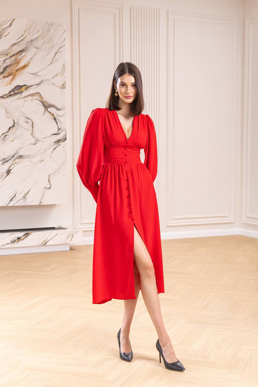 Woman in a red dress standing in a room with marble wall.