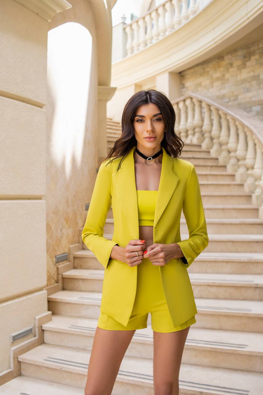 Woman in a yellow outfit standing on a staircase with classical architecture.