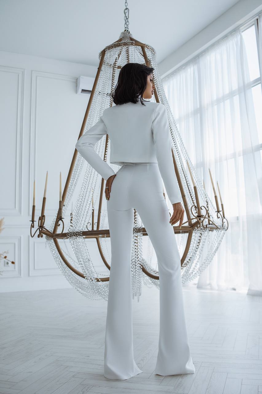 Person wearing a white outfit standing in a bright room with a hanging chair.