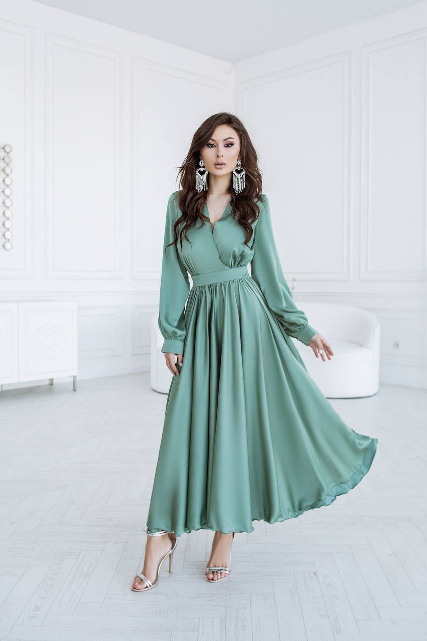 Woman wearing a long green dress in a minimalistic room.