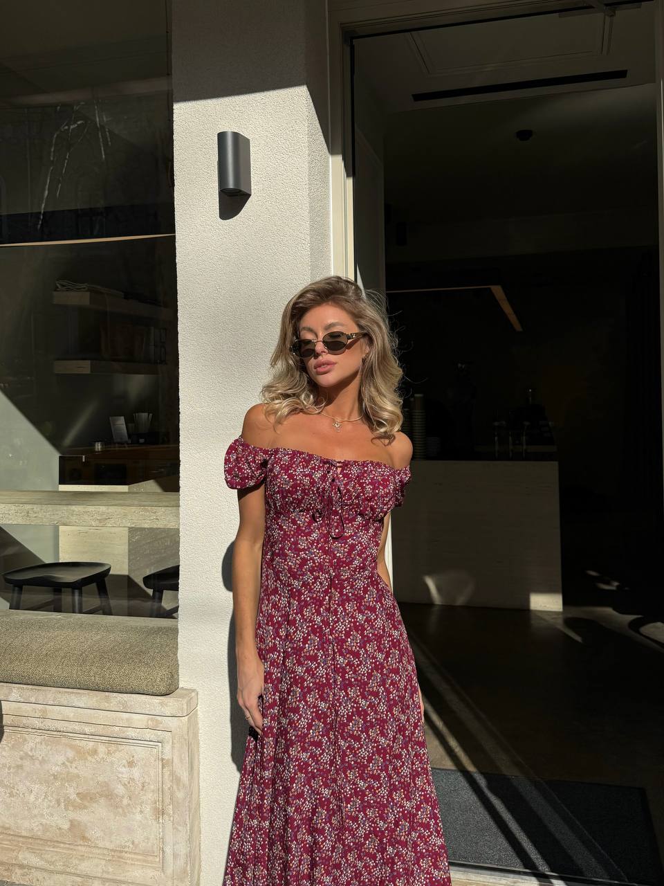 Woman in a floral dress standing outside a modern building.