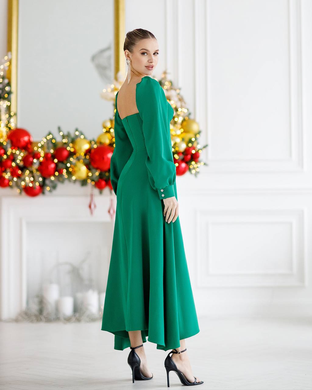 Woman in a green dress standing in a decorated room with Christmas decorations.