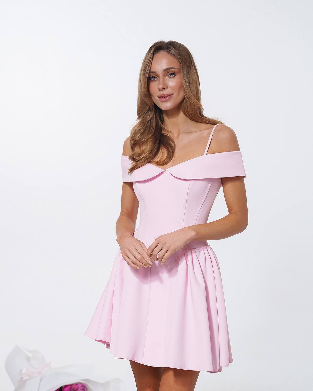 Woman wearing a pink off-shoulder dress against a white background