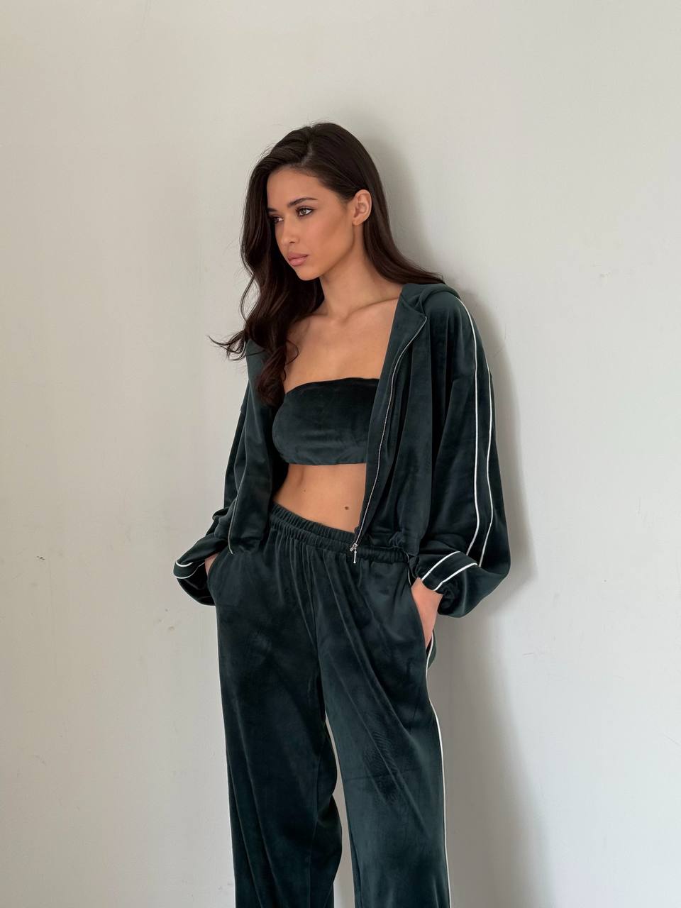 Woman wearing a dark green tracksuit against a plain background