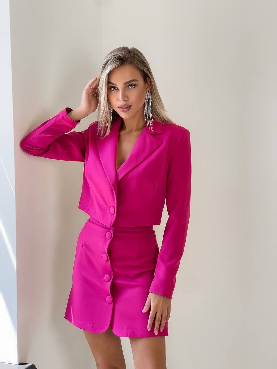 Woman wearing a bright pink suit against a neutral background