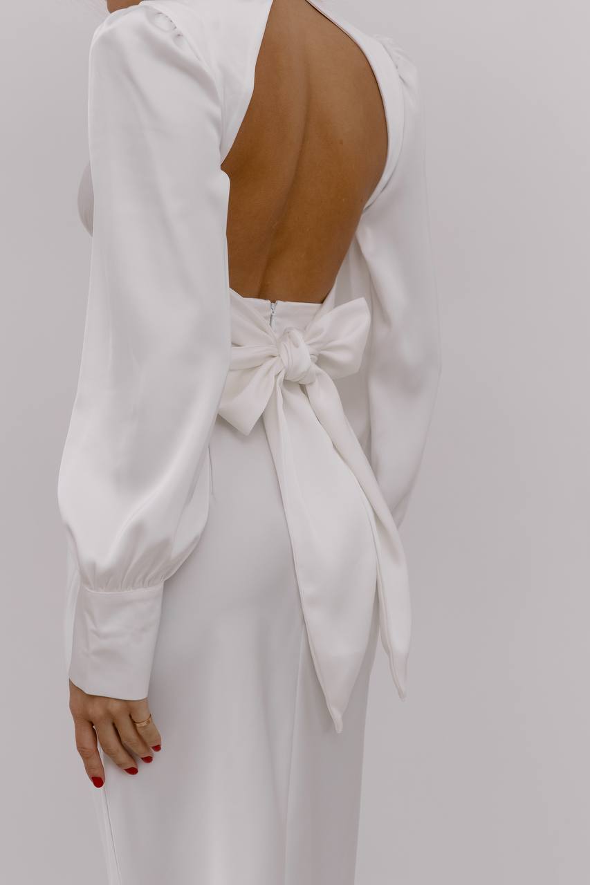 White dress with a bow detail on a plain background