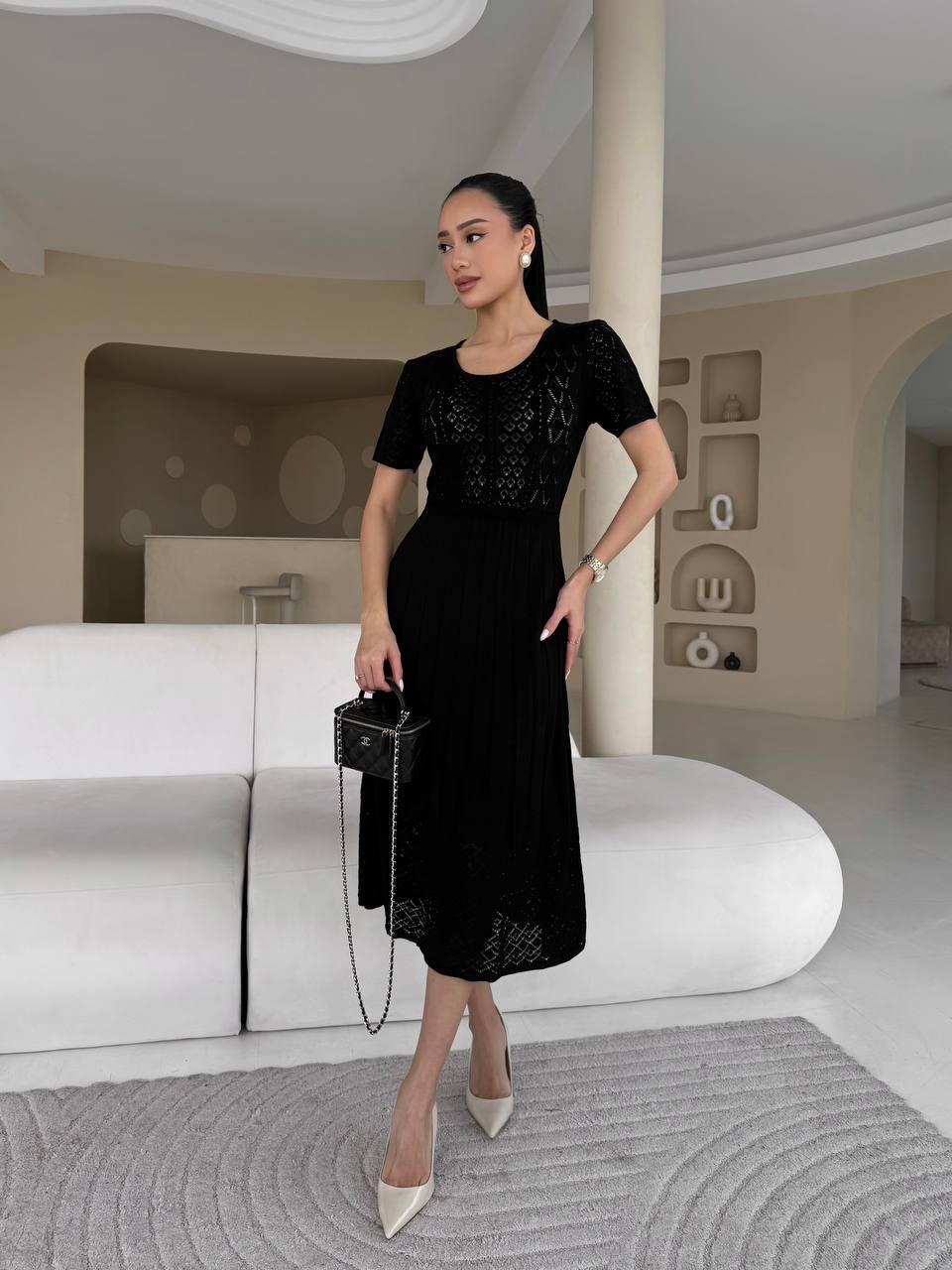 Woman in a black dress standing in a modern interior setting