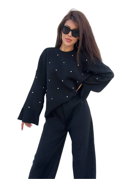 Woman wearing a black outfit with white embellishments on a white background