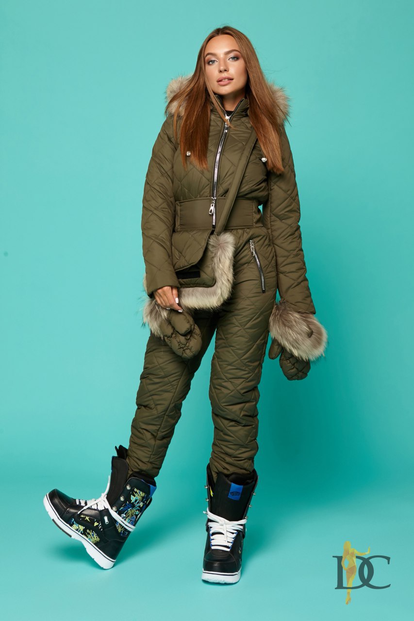Woman wearing a green winter outfit with fur-lined hood and mittens on a teal background