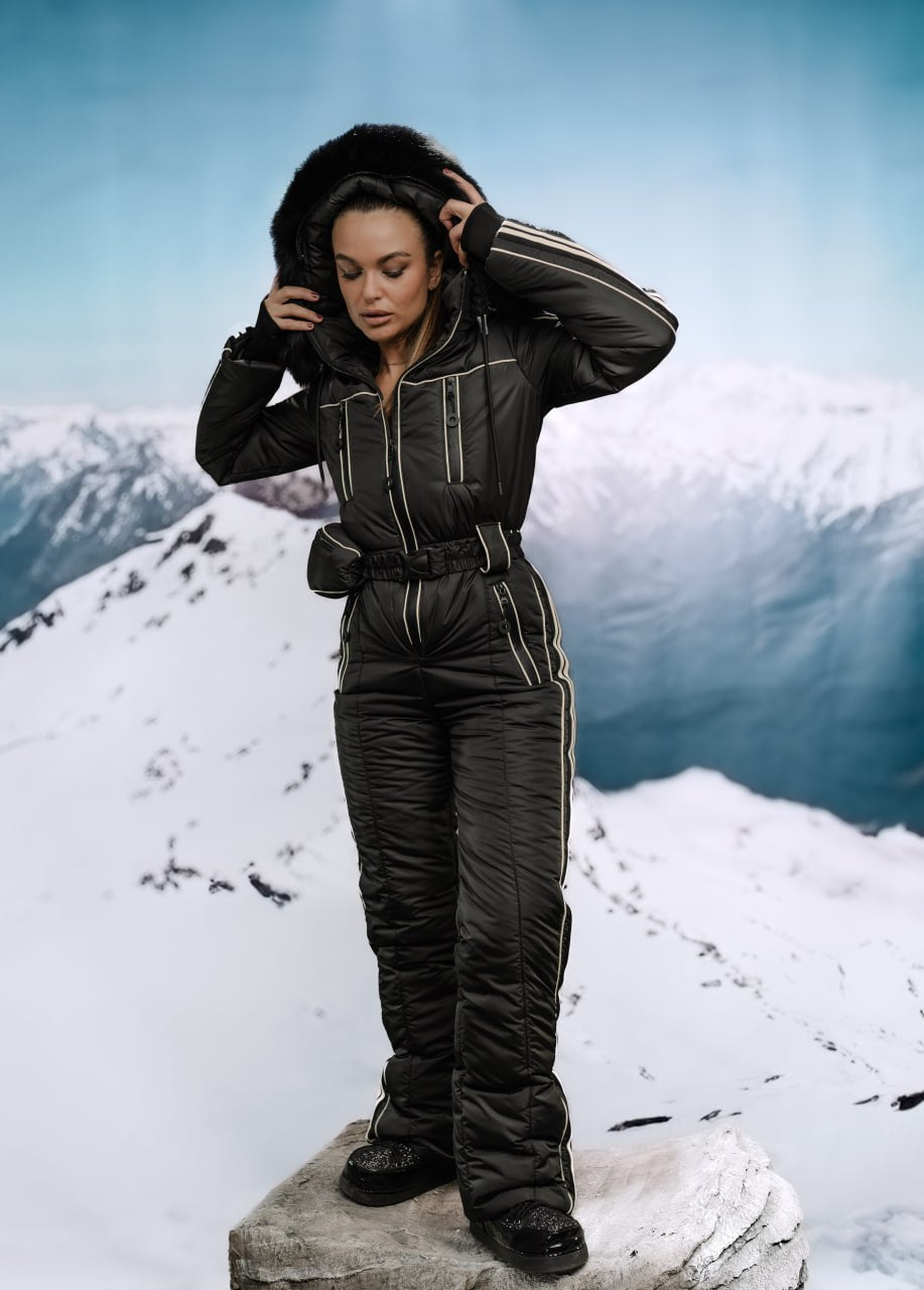 Person wearing a black snowsuit on a snowy mountain peak