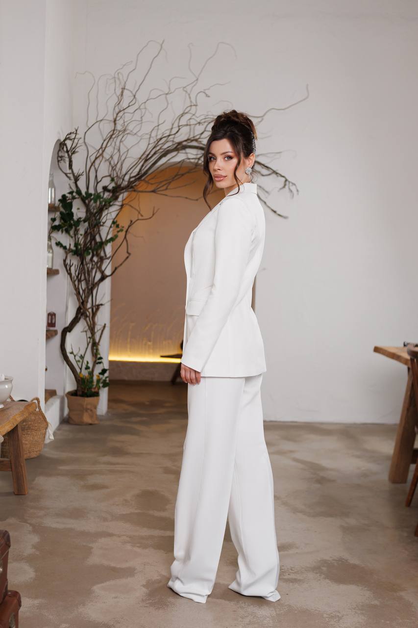 Woman in a white suit standing in a room with minimal decor