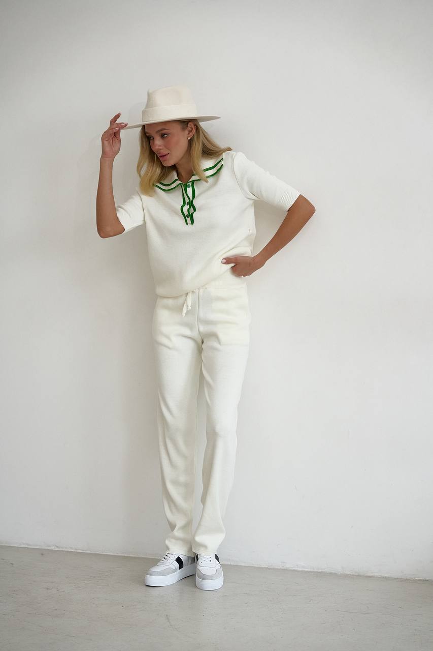 Woman in a white outfit with green accents against a plain background