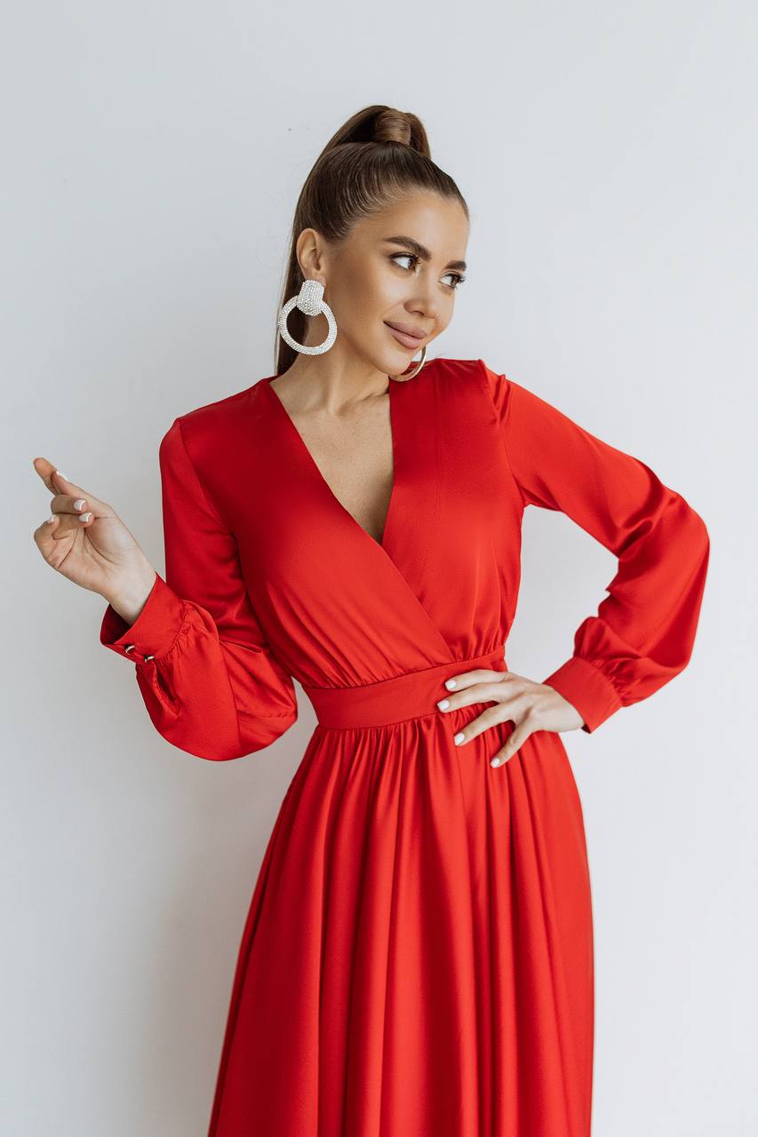 Woman wearing a red dress with long sleeves against a white background