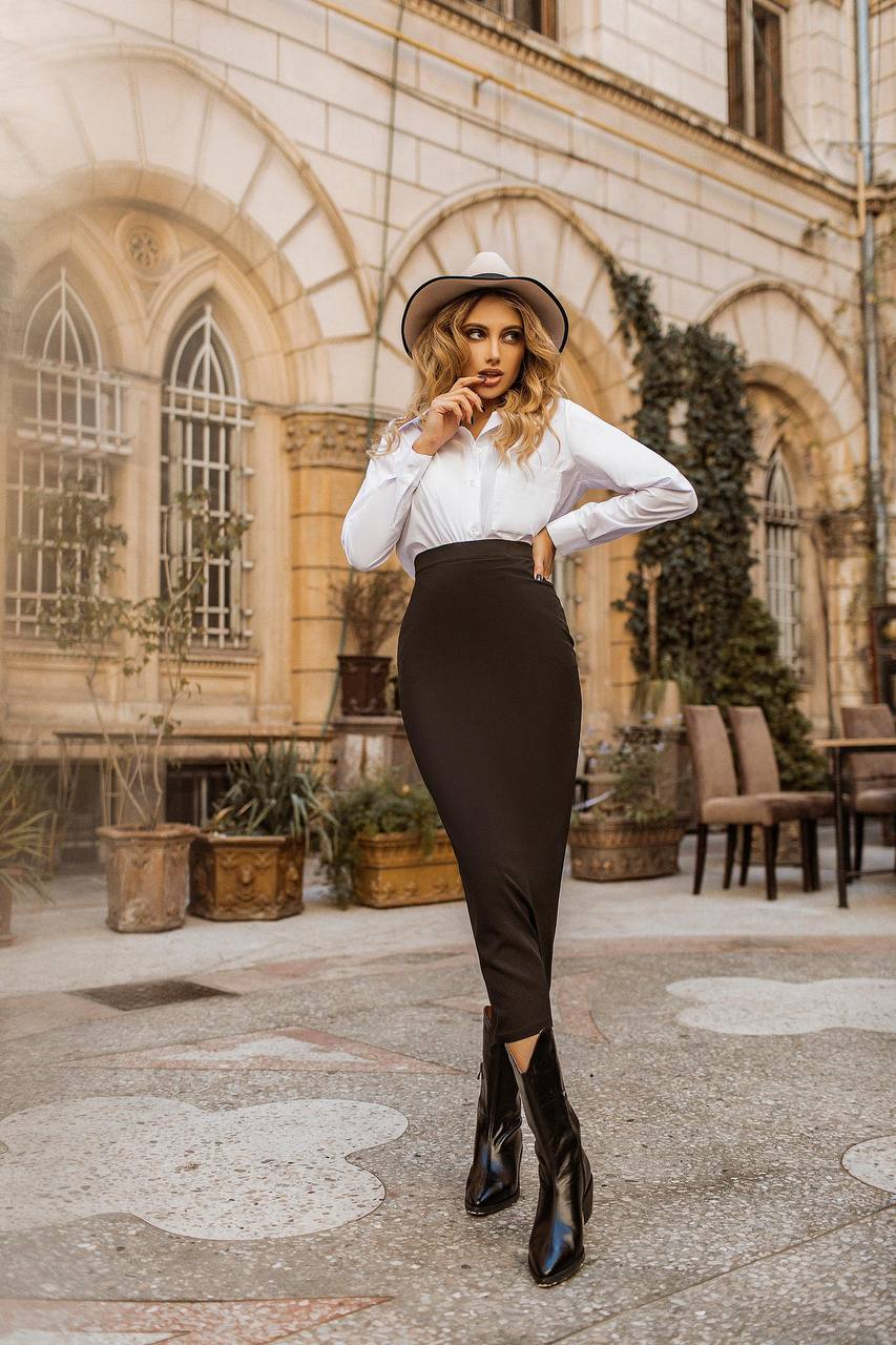 Woman in a stylish outfit standing in an outdoor setting with architectural elements.