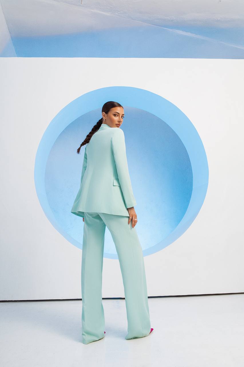 Person wearing a light blue suit standing in front of a circular blue light fixture.