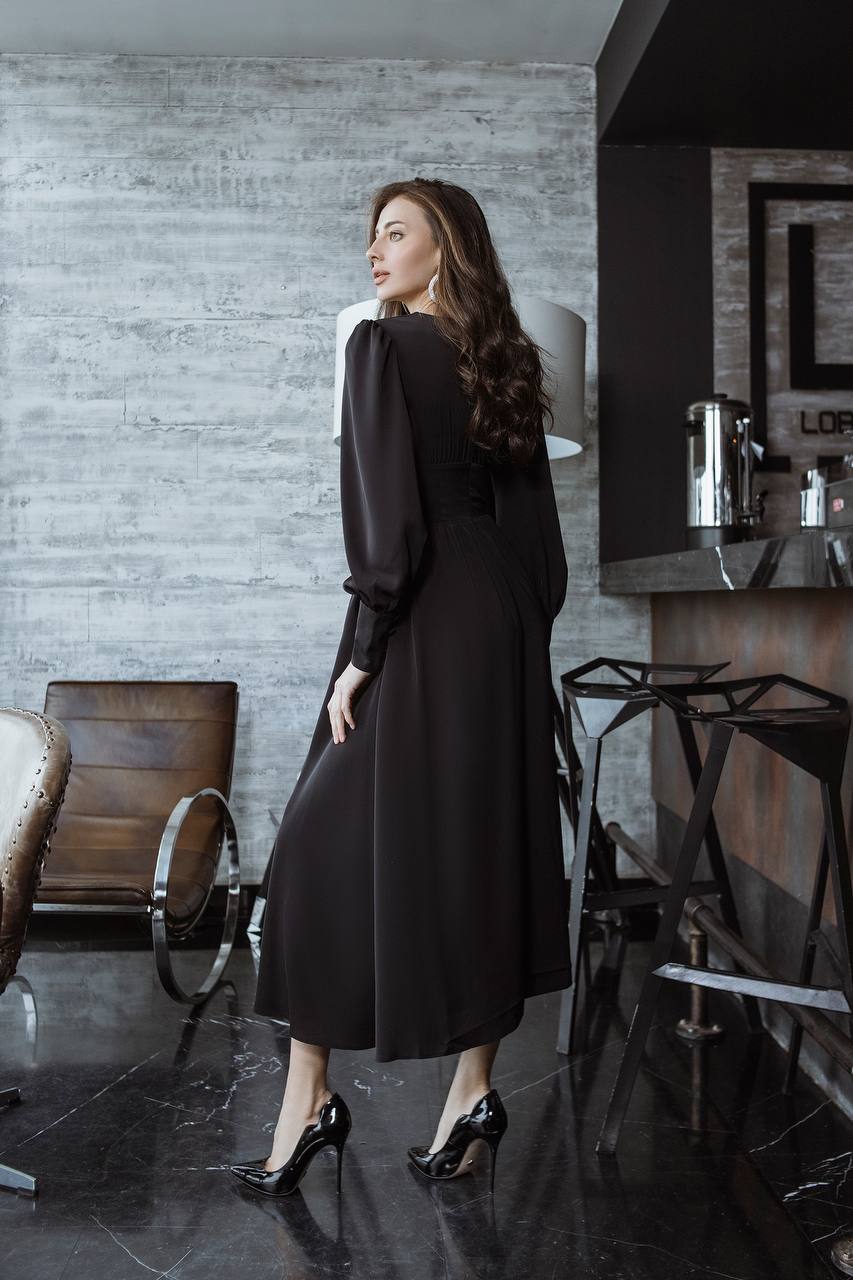 Woman in a black dress standing in a modern interior setting