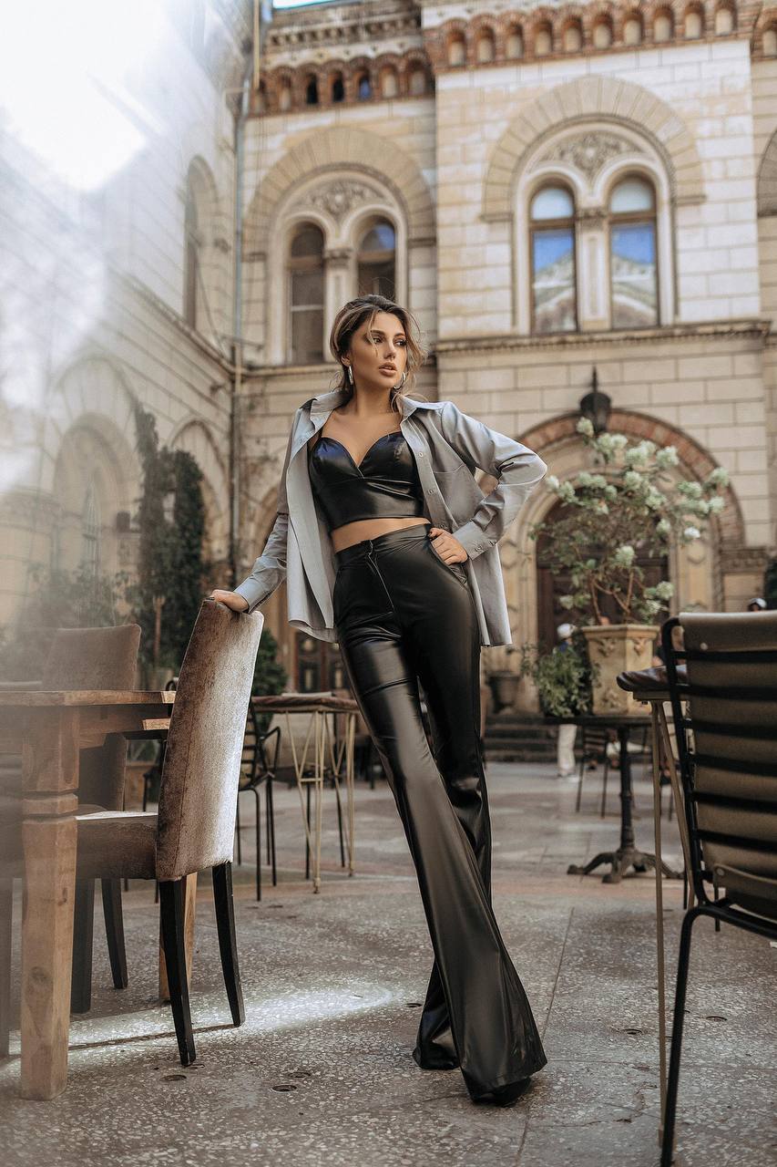 Woman in a stylish outfit standing in an outdoor setting with architectural background
