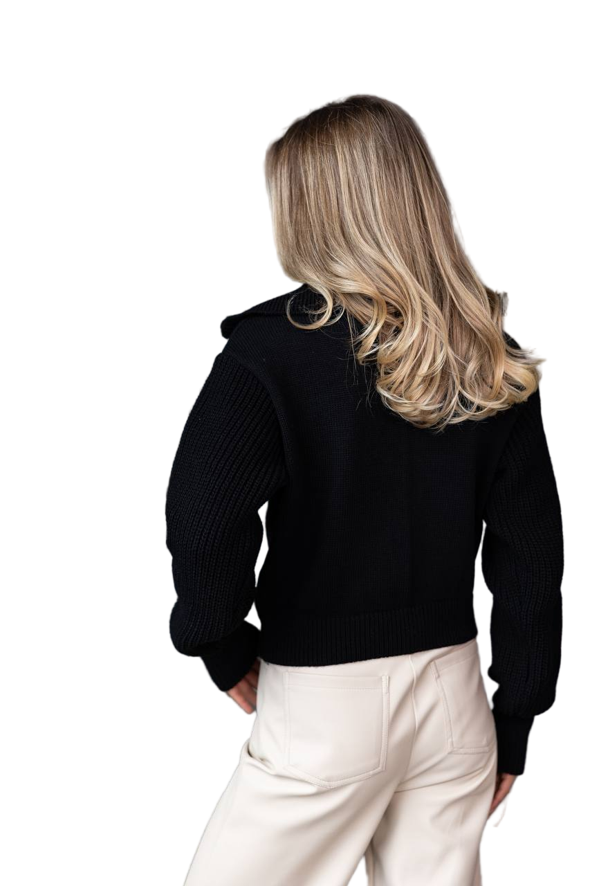 Person wearing a black sweater and white pants on a white background