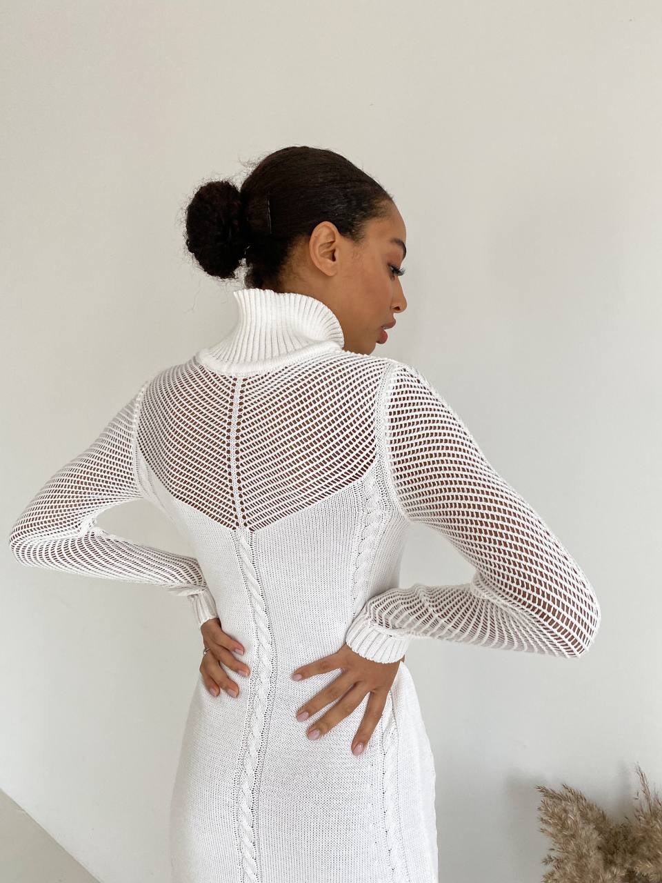 Woman wearing a white dress with mesh back panel against a plain background