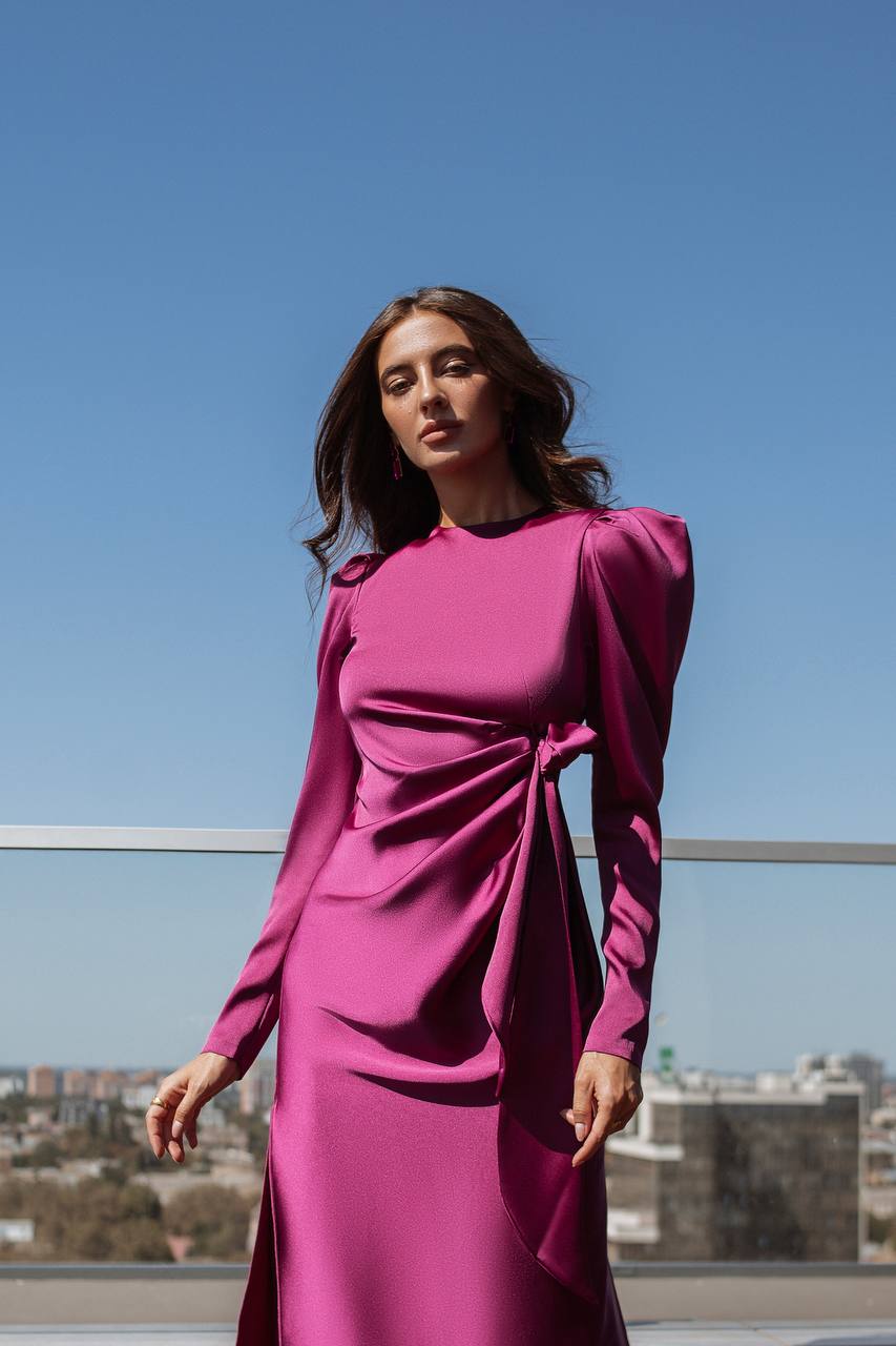 Woman wearing a pink dress on a rooftop with a clear blue sky