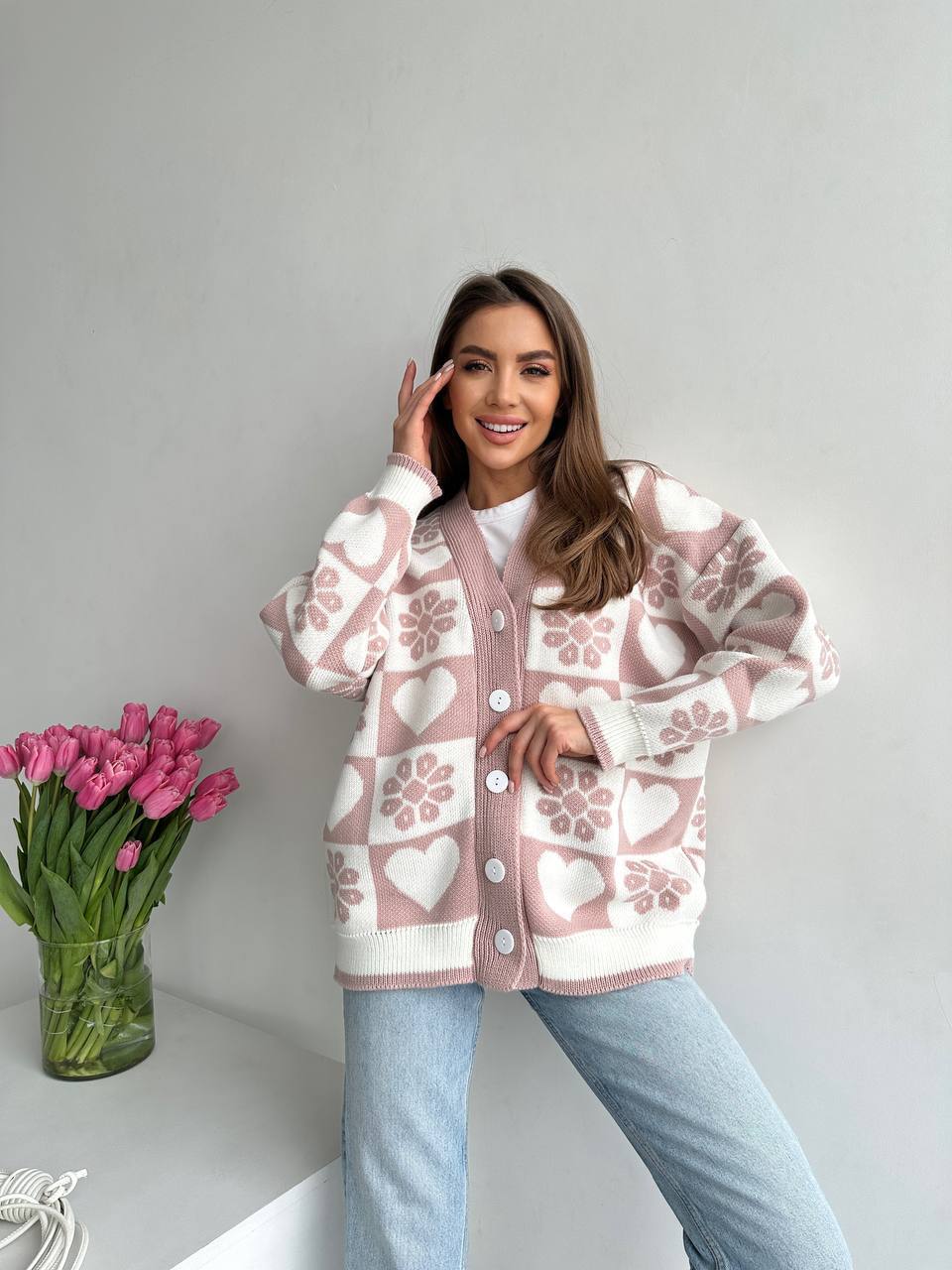 Woman wearing a patterned cardigan with pink tulips on a white background
