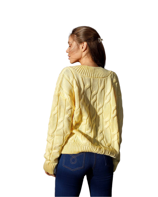 Woman wearing a yellow cable knit sweater on a white background