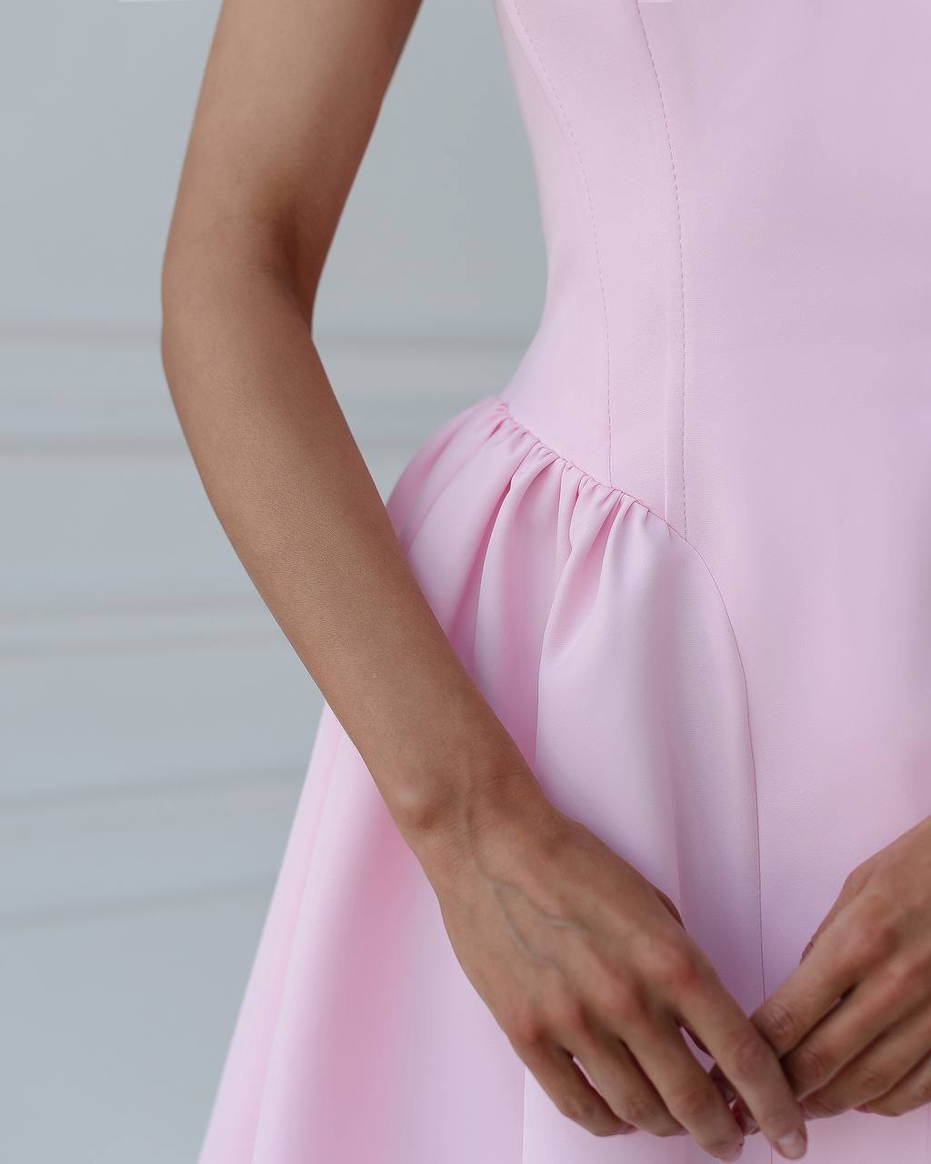 Close-up of a person wearing a light pink dress with a blurred background