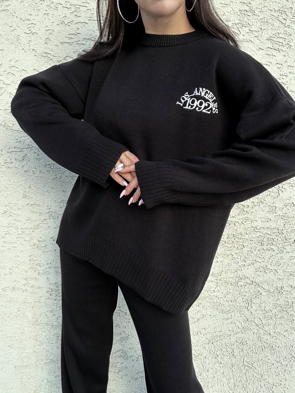Person wearing a black sweater with 'Los Angeles 1992' text against a light gray background