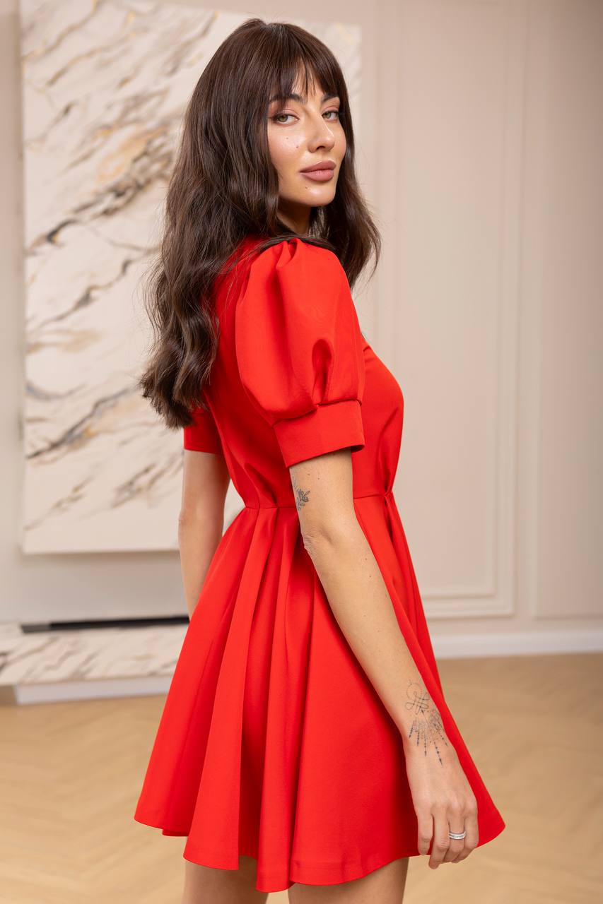 Woman wearing a red dress in an indoor setting with a neutral background