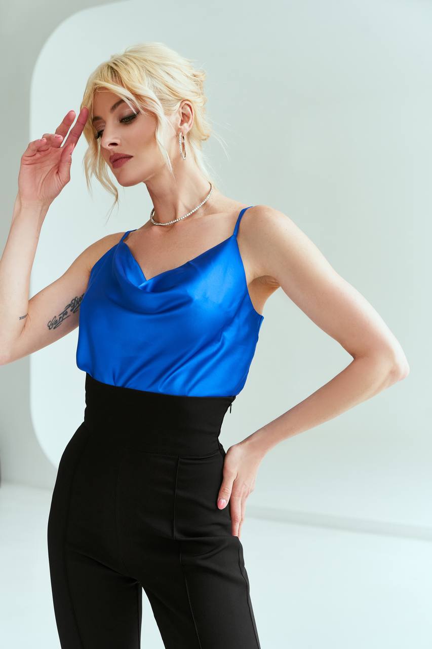 Woman wearing a blue top and black pants against a white background