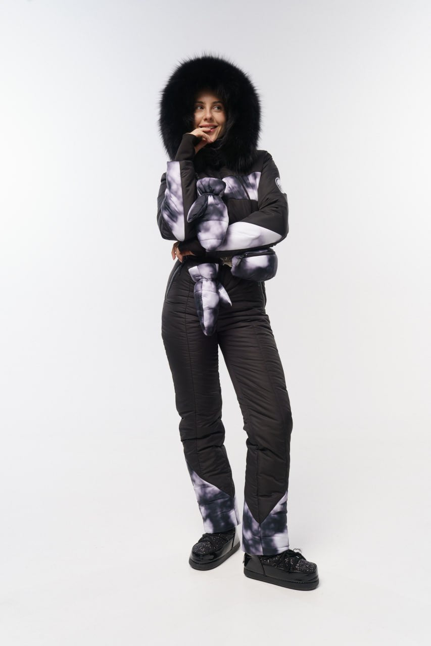 Person wearing a black and white patterned outfit with a fur-lined hood on a white background